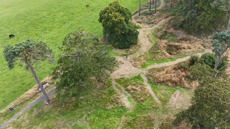 Bovenaanzicht van gemaaide paden tussen oude bomen en grasland op natuurbegraafplaats Cothiemuir Hill