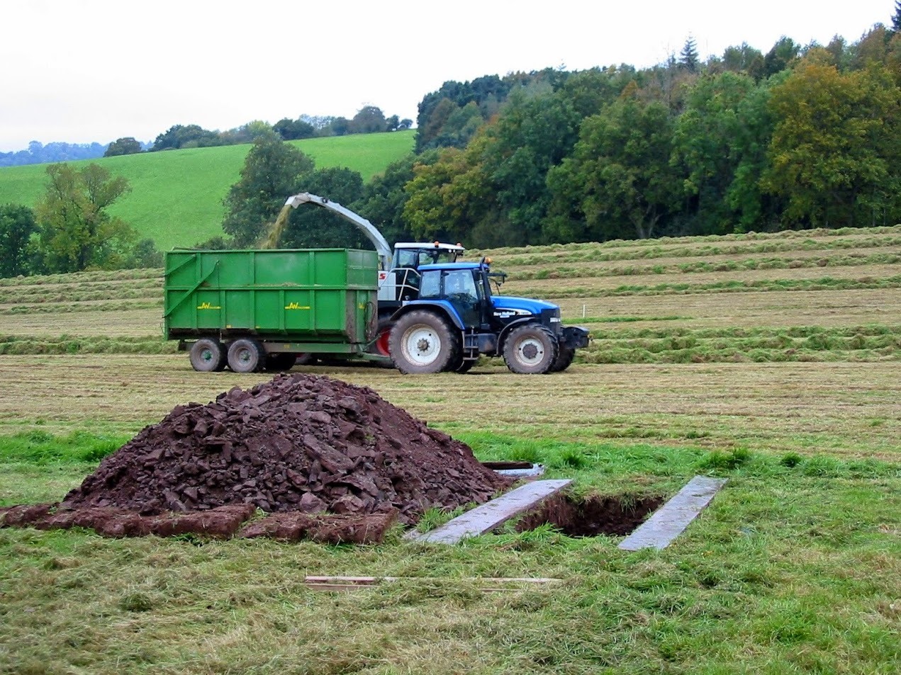 Tractor met kipper bij grondwerk op een natuurbegraafplaats in een weiland