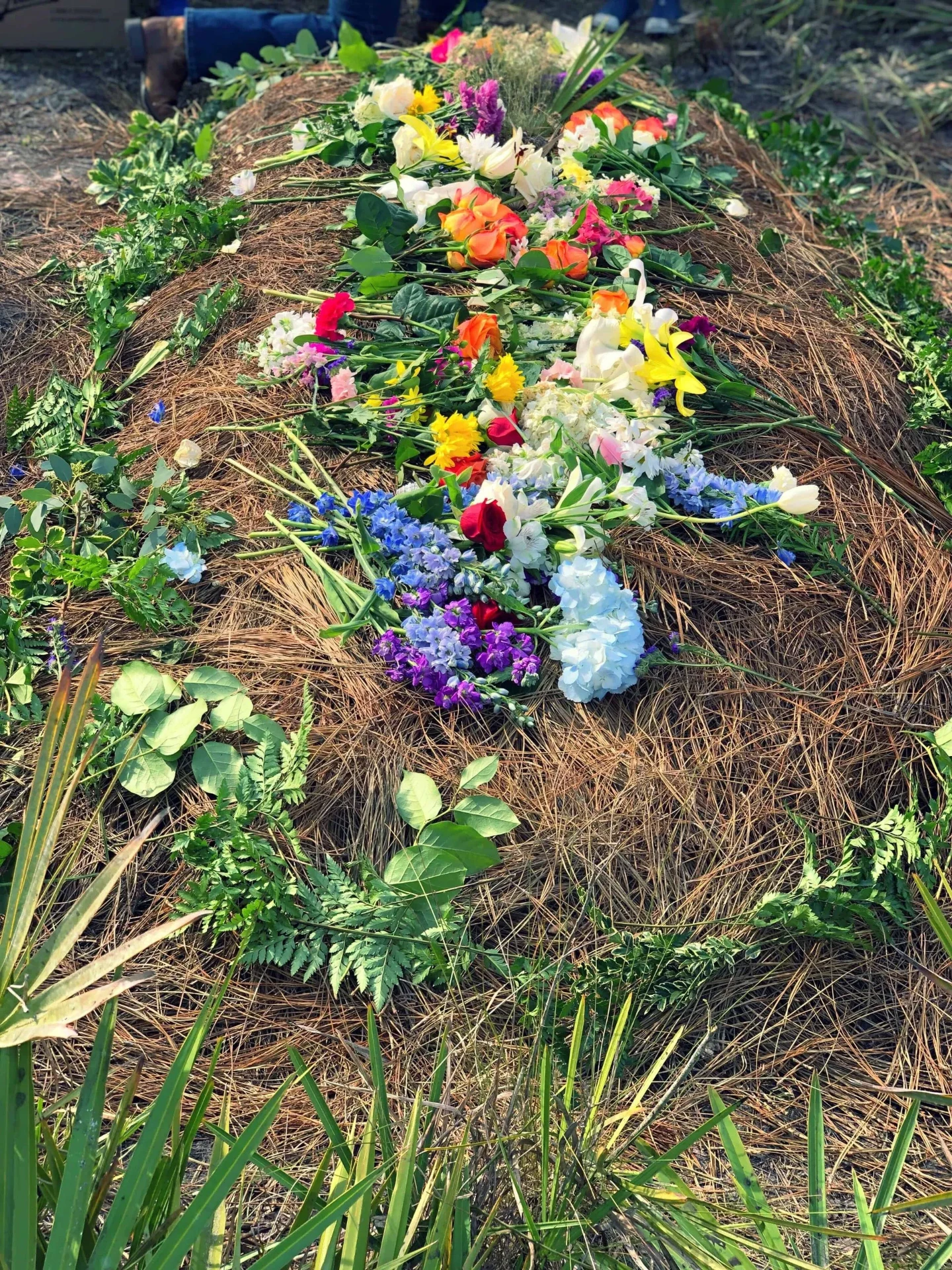 Grafheuvel bedekt met veldbloemen en varens in een natuurlijke omgeving